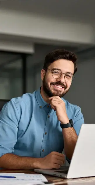 hombre sonriente frente a portatil en entorno de oficina
